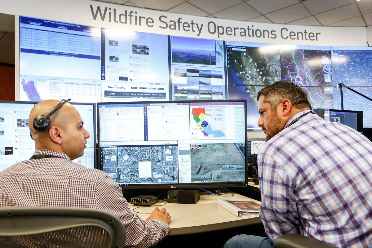 Neal Narayan and Anthony Malnati, Sr. wildfire safety operation center analysts, monitor a small fire on the 16 screen video wall and as well their stations as the media receives a tour of the hub PG&E set up in its San Francisco headquarters last year to monitor for wildfires on Monday, August 5, 2019 in San Francisco, Calif.