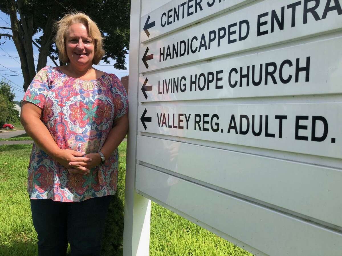 Valley Regional Adult Education has moved all its programs to one location, the Richard O. Belden Cultural Center, 54 Grove Street. Director Debra Hansen stands in front of the sign for her educational organization’s new home.