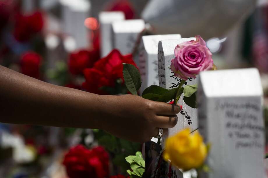 A woman places a rose on the crosses honoring the El Paso shooting victims at the makeshift memorial. Photo: Marie D. De Jesús/Staff Photographer