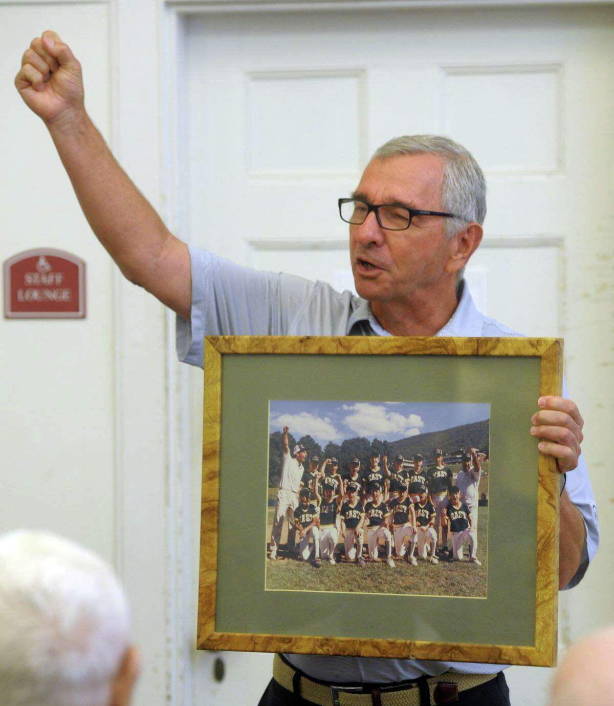 Tom Galla, who coached the Trumbull National baseball team that won the 1989 Little League World Series, holds a photograph of the team as he speaks during the regular Silver Sluggers program at the Derby Public Library last week. This month marks the 30th anniversary of Trumbull’s World Series Championship.