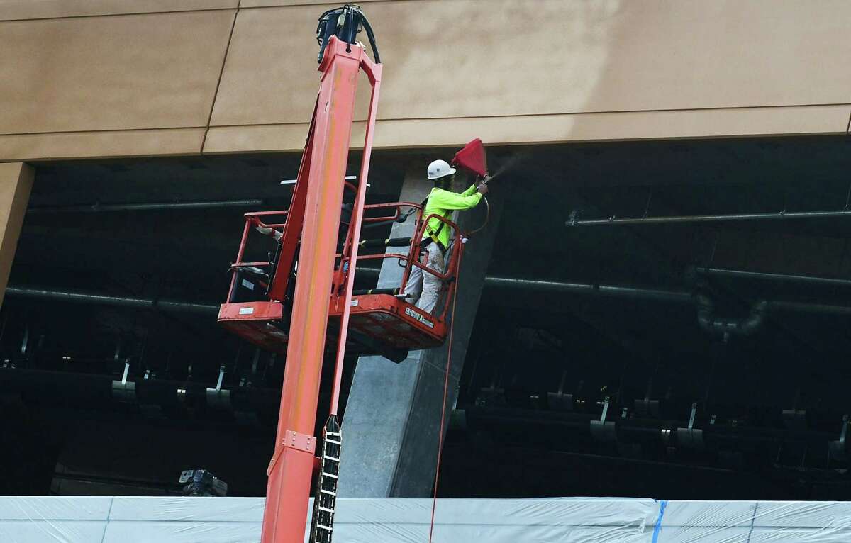 Construction workers with Brookfield Properties paint the garage exterior at the SoNo Collection mall on July 30, in Norwalk. The one-million-square-foot mall plans to open in the fall of this year.