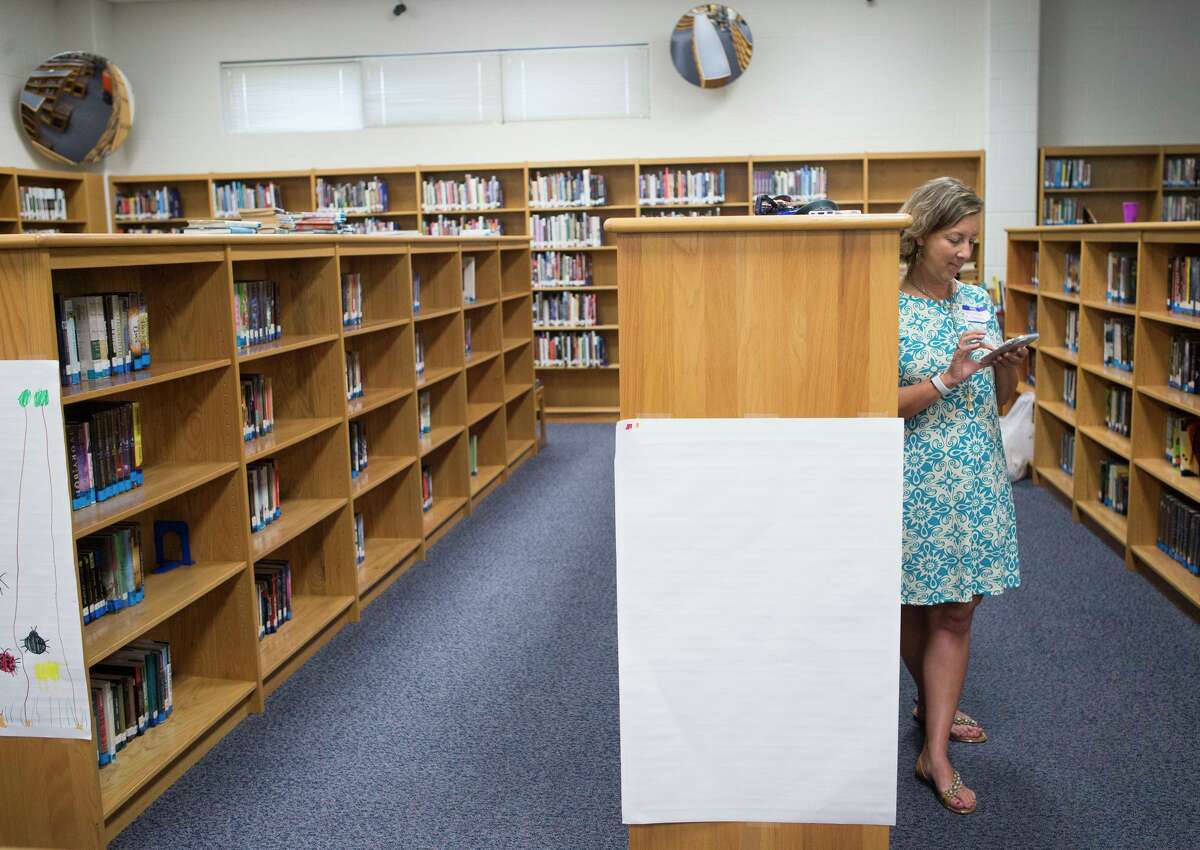 Jennifer Saeger, a special needs teacher, takes a moment after lunch to look at her phone in the middle school library at Randolph Field ISD during a new teacher induction Thursday.Veteran teachers in the district will receive some of the highest increases in pay given by any area school system. Rebecca Slezak/Staff photographer