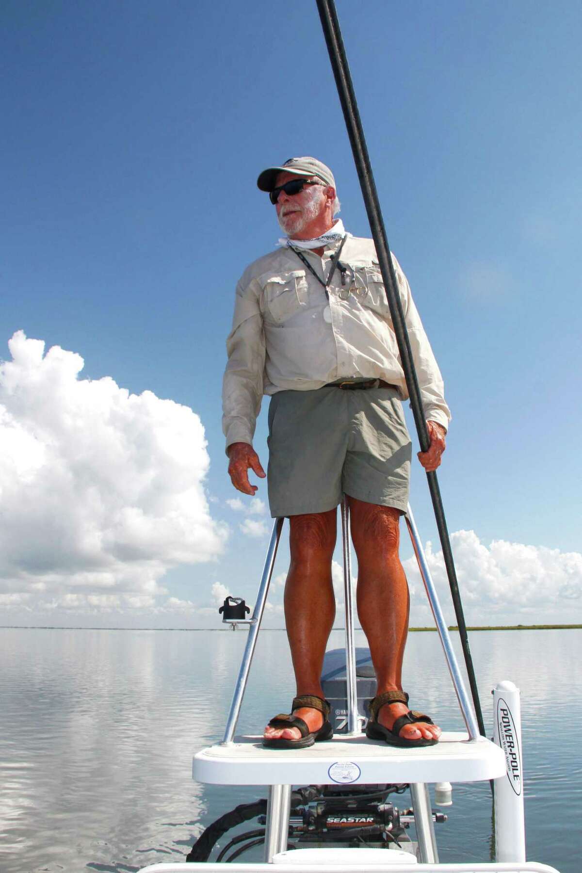 Chuck Naiser, who has spent more than 50 years fishing and guiding anglers on the bays of Texas central coast, takes a break from poling his skiff to search the shallow flats for signs of feeding redfish.