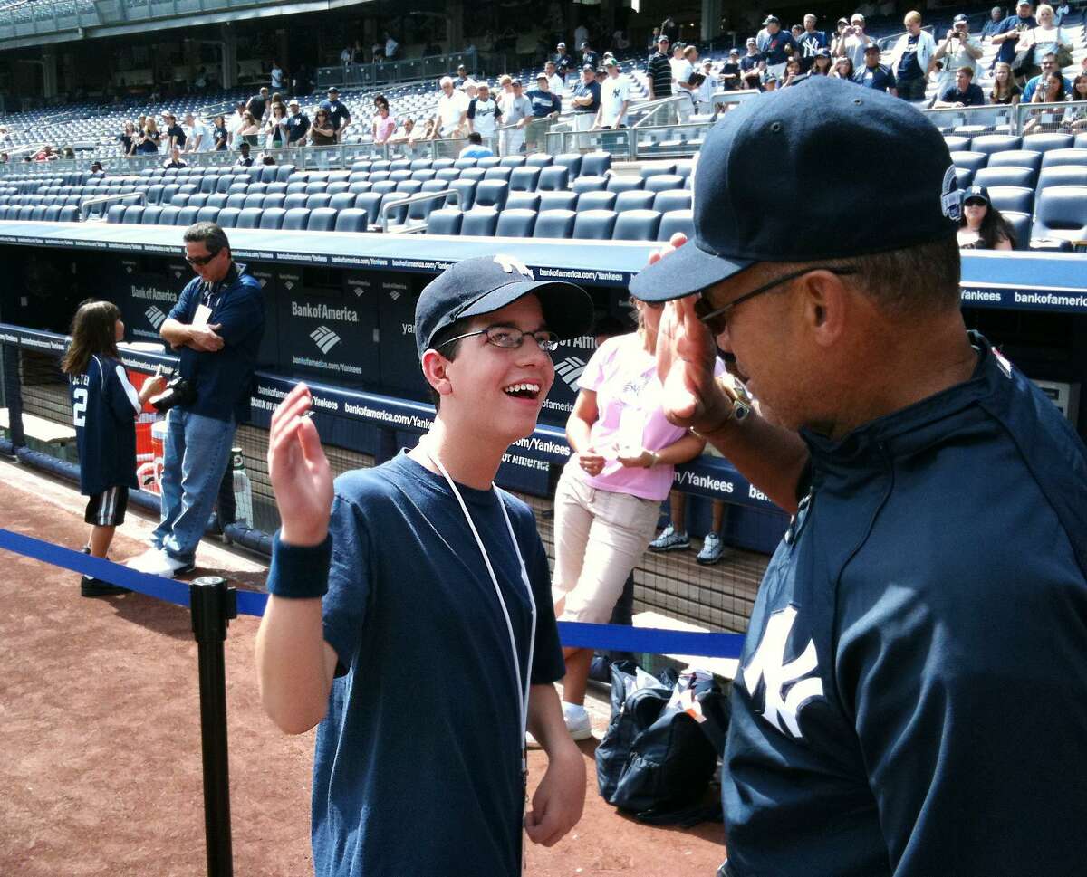 Justin Nemchek of Stamford, left, slaps hands with baseball legend, Mr. October, Reggie Jackson, right, at Yankee Stadium prior to game against Detroit. Nemchek a 14-year-old Stamford boy will undergo a serious surgery at Stamford Hospital aimed to eliminate or reduce some of his 40 daily seizures and remove a life-threatening clump of blood vessels in his brain.