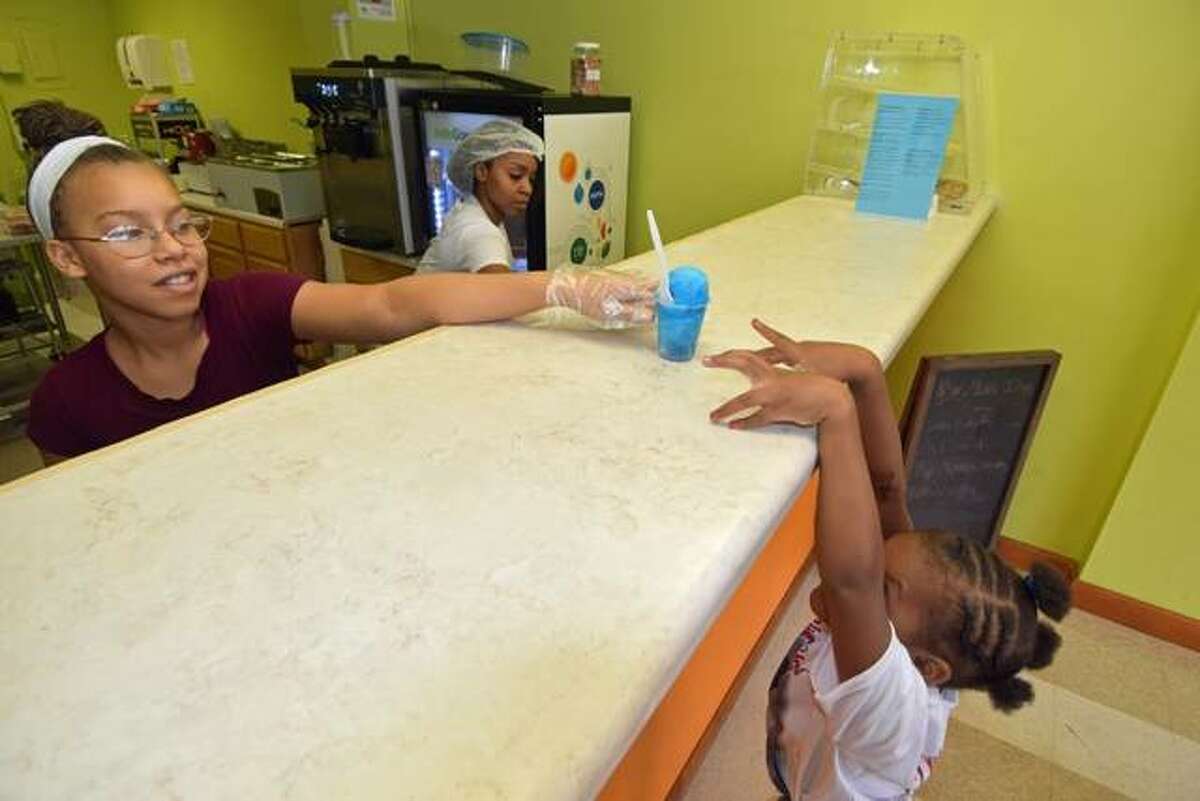 C.C., after whom the restaurant is named, serves 5-year-old Chyna Dandridge, of Alton, during the ribbon-cutting on Saturday for CC’s Icees Galore at 1626 Main St., Alton.