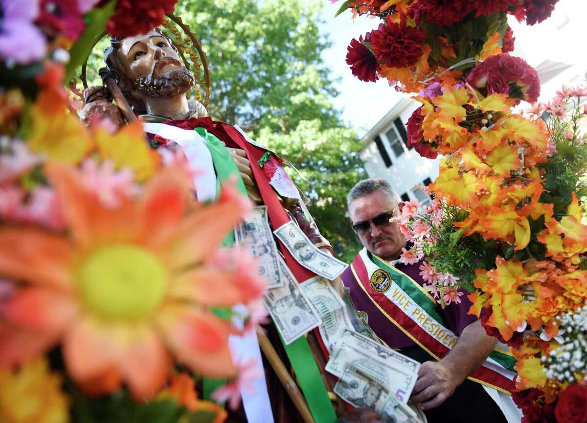 Mario Montonarano pins money to the statue of St. Roch as the 110th annual St. Roch Church procession moves through the streets in the Chickahominy section of Greenwich, Conn. Sunday, Aug. 11, 2019. To close out the Feast, the church paid tribute to St. Roch with a procession featuring a statue of St. Roch and music from the Dixie Dandies. Onlookers crowded the streets and pinned money to ribbons on the statue as the procession made its way through town.