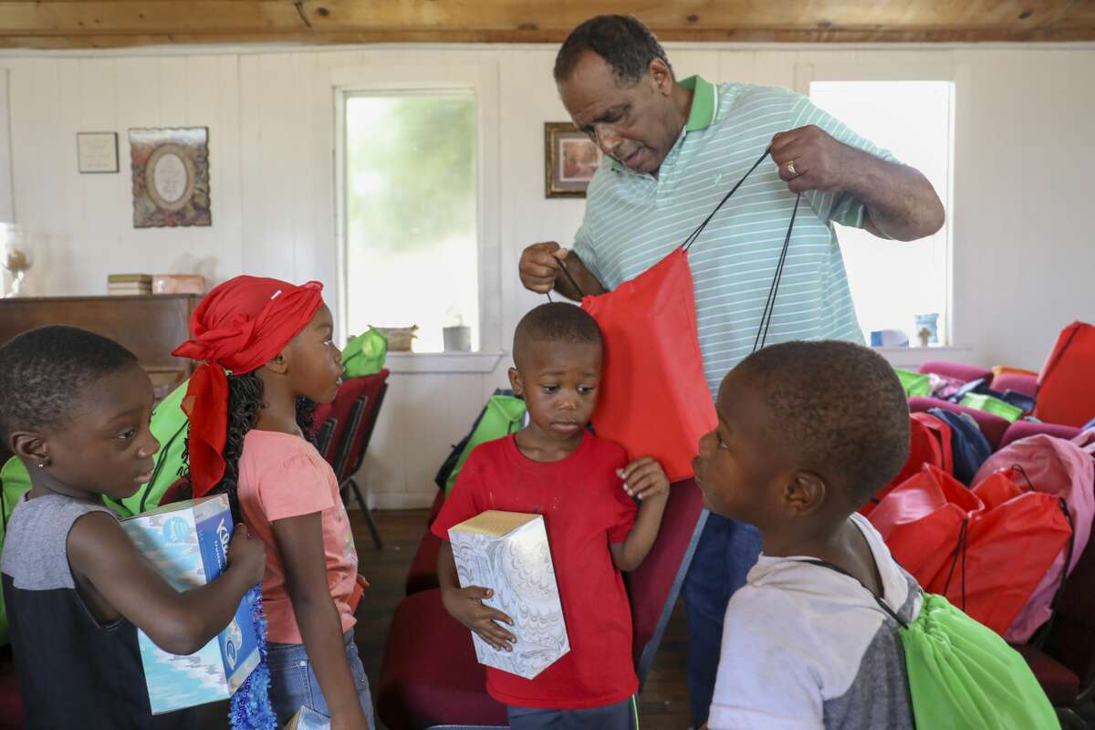 Pastor Dennis Hodges distributes free backpacks to children during Cops, Kids and Bar-B-Q was Saturday, Aug. 10, 2019 at Mount Moriah Disciples of Christ.