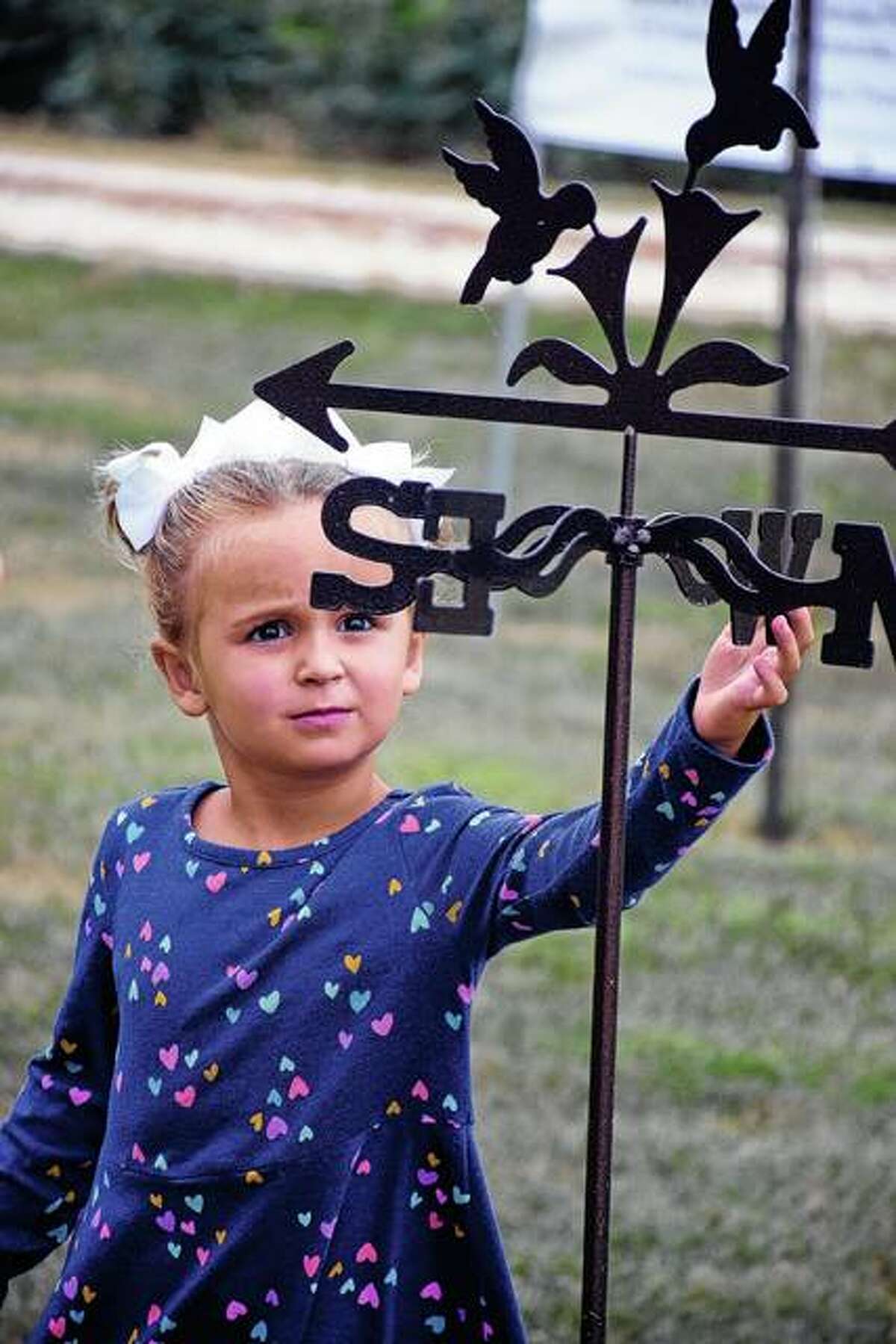 Three-year-old Ella Biedermann of Washington, who was in Illinois visiting her grandparents, plays with a hummingbird weather vane during Sunday’s Hummingbird Festival.