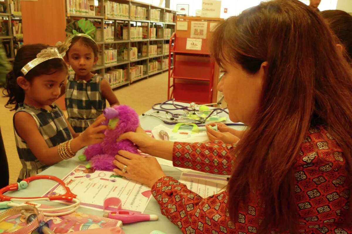 Kim and Nicole Winkeleer treat Aarika's purple monkey at the Doc McStuffins stuffed animal clinic at RidgeCon on Saturday, Aug. 10.