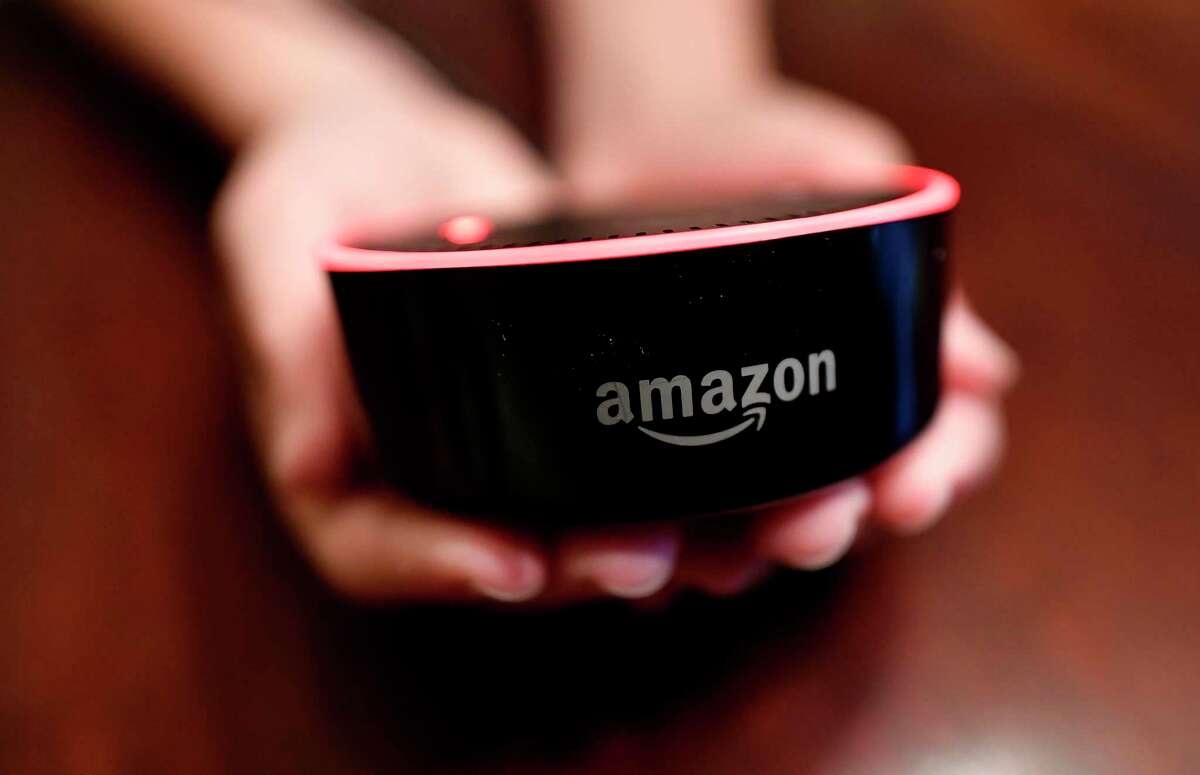 FILE- In this Aug. 16, 2018, file photo a child holds his Amazon Echo Dot in Kennesaw, Ga. Technology companies are pushing the “smart home,” selling appliances and gadgets that offer internet-connected conveniences you didn’t know you needed. (AP Photo/Mike Stewart, File)