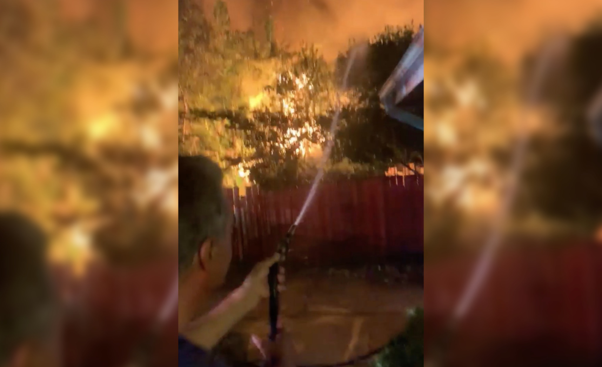 Neighbor uses garden hose to protect his home as fire rips through