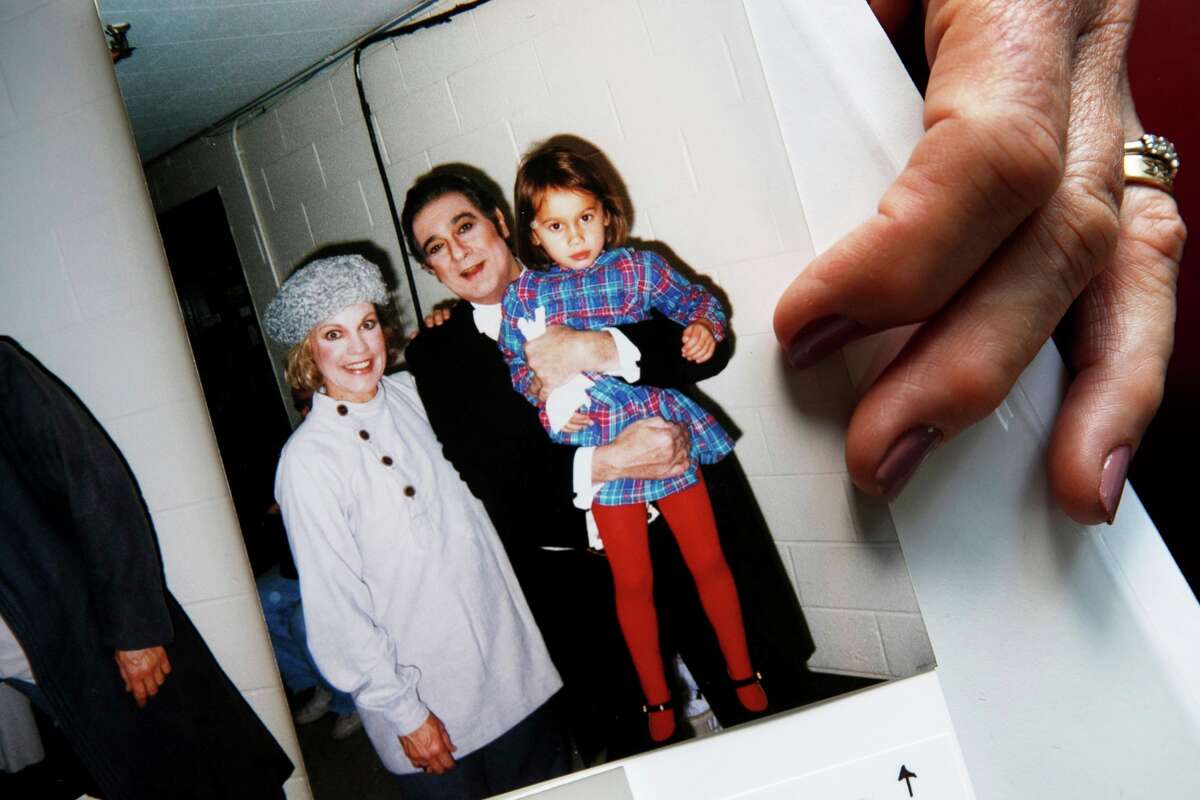 Opera singer Patricia Wulf holds a 1998 photo of herself, left, with opera star Placido Domingo holding her 4-year old daughter after a performance of "Fedora" at the Washington Opera, at her home in rural northern Virginia, on Friday, July 12, 2019. In interviews, Wulf said Domingo repeatedly propositioned her as she walked off stage, often knocked on her dressing room door asking to come in and she tried to dodge his advances by hiding from him. She said she repeatedly told the opera superstar who was also artistic director at Washington Opera that she wasnât interested and each time would wonder, âDid I just ruin my career?â (AP Photo/Jacquelyn Martin)