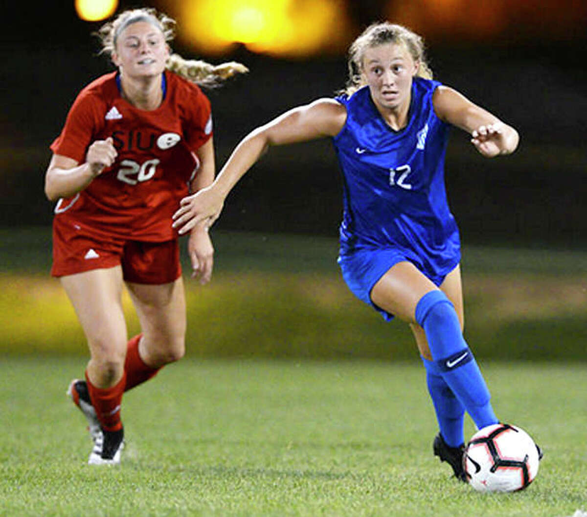 Brianna Halverson pf Saint Louis University (12) moves the ball past SIUE’s Courtney Benning in exhibition action Tuesday night at Saint Louis U’s Hermann Stadium. The Billikens beat SIUE 2-0.