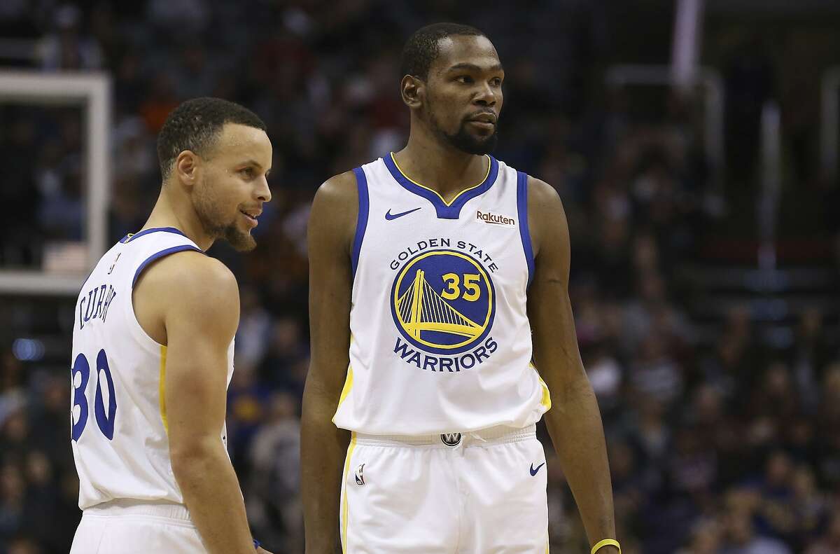 In this Feb. 8, 2019, file photo, Golden State Warriors guard Stephen Curry and forward Kevin Durant pause during the first half of an NBA basketball game against the Phoenix Suns Friday, Feb. 8, 2019, in Phoenix. 