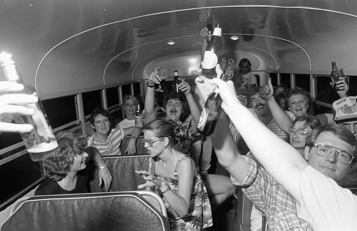 06/11/1983 - Revellers toast the start of the First Annual Foam Rangers Pub Crawl as the bus takes them to their next stop.