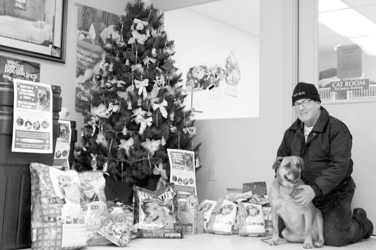 Pet Food Drive: Assistant Animal Control Officer Ed Carter and Baby Girl, a boxer mix awaiting a loving home at the Benzie County Animal Shelter, pose with some of the many items donated to the shelter during the holiday pet food drive. A big thank you to Glen’s Market in Frankfort, Shop N Save in Benzonia and the Honor Family Market in Honor for help collecting the many bags of dry dog and cat food, canned pet food and treats and a heartfelt thank you to everyone who made donations during the drive. Photo/Colin Campbell