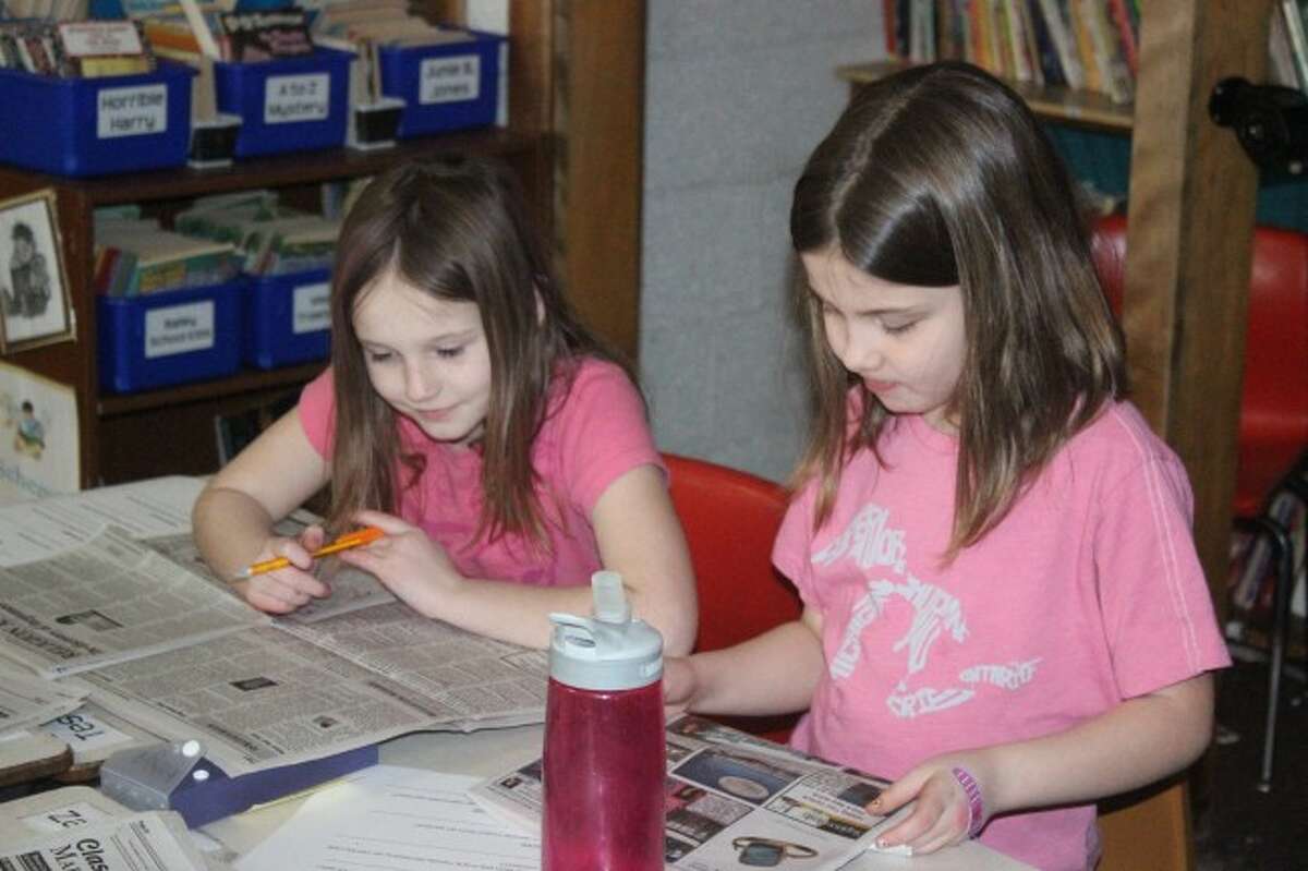 LOOKING FOR EXAMPLES: Platte River Elementary students study the Record Patriot for the NIE lesson. The students are learning what goes into making a newspaper.