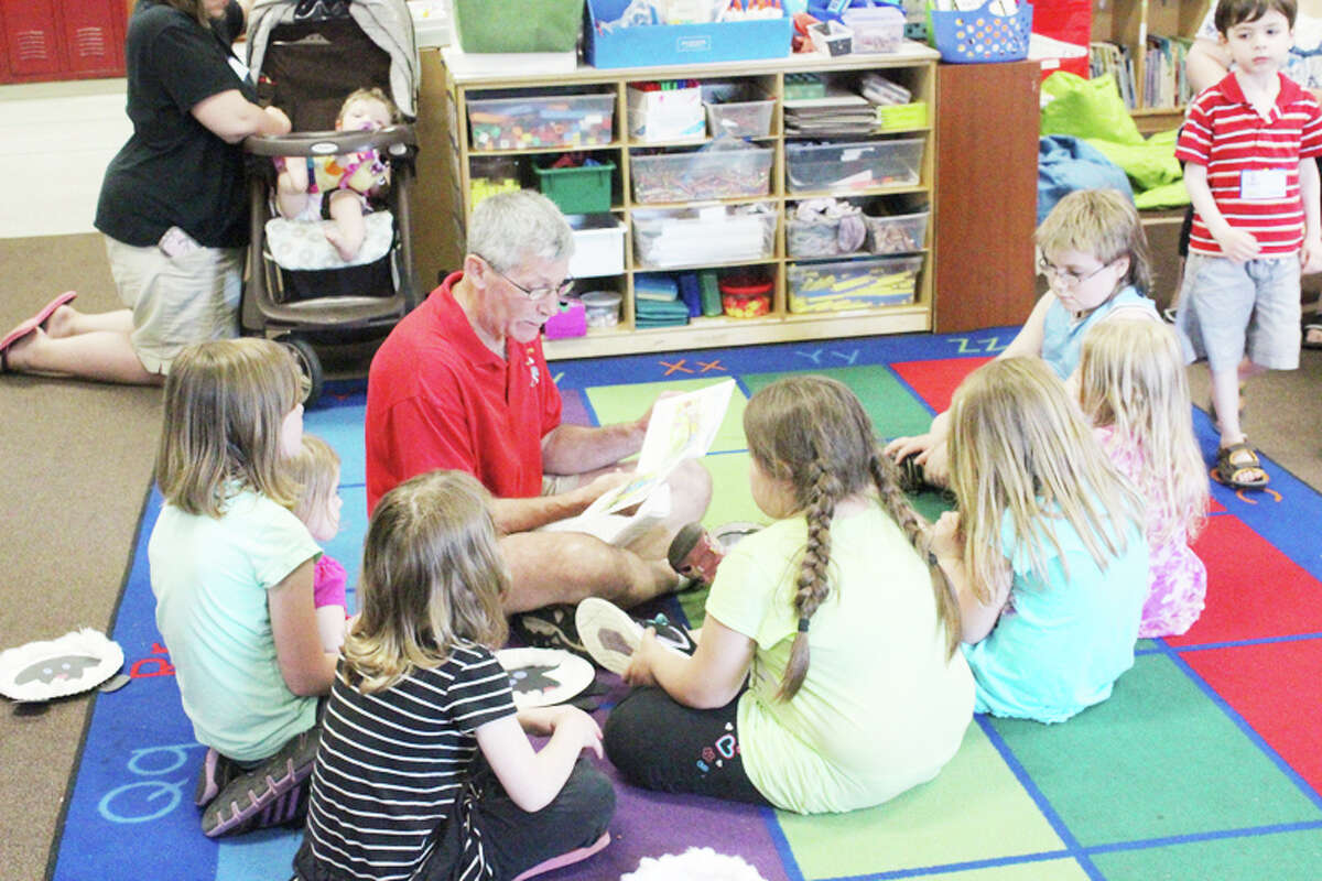 READING: Retired Platte River Elementary School principal Phil Cook reads “The Little Engine that Could” to children during the school’s book fair. The major focus of the event was to help introduce students to reading and to encourage more reading at home between children and their parents. (Photos/ Bryan Warrick)