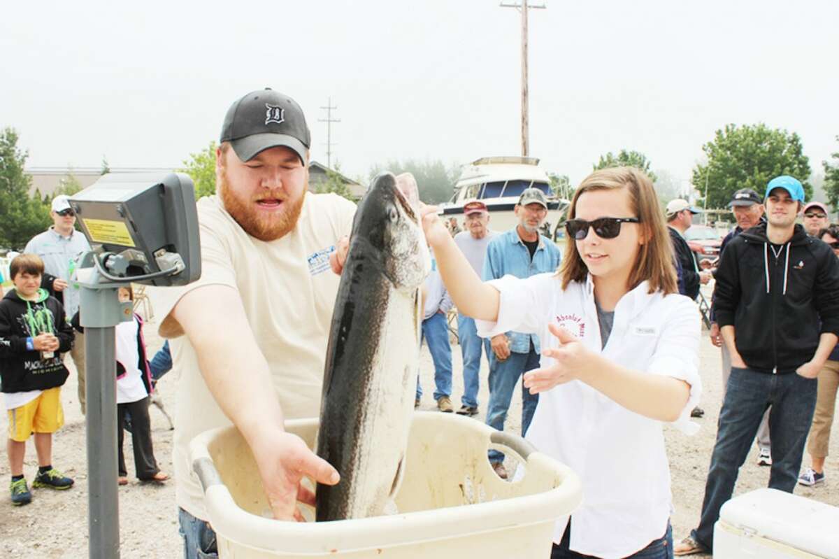FISHING TOURNEY: Carson Cutting, from the Absolute Miss, hands her team’s catch to Steve Joslin, the Grand Traverse Area Sports Fishing Association official weighing in the fish at the The David Bihlman Memorial Fishing Tournament held in Frankfort Sunday.