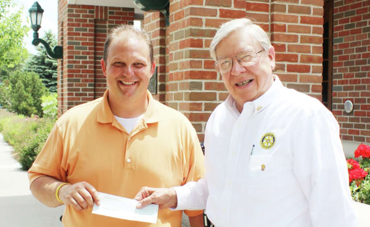 TRADITION OF HELPING: Ned Edwards, president of the Friendly Frankfort  hands Josh Mills, superintendent of the City of Frankfort, a check for $1,170 to install two more brick pavers under the trees in the downtown district. (Photo/Colin Merry)