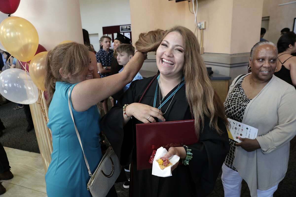 Tany Rios Castro gets help from her mom Rocio Castro Mendoza with straightening out her hair after putitng on a necklace after the graduation ceremony for about a dozen working professionals in the Working Scholar program sponsored by Study.com In Mountain View, Calif., on Thursday, August 15, 2019. The Working Scholars program offers free tuition for vulnerable working adults (many entry-level gov employees) to finish bachelor degrees online through Study.com.