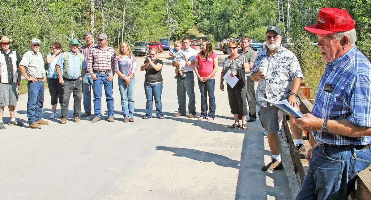 SPEECH MAKER: Road commissioner Roger Griner, extreme right, reads the accomplishments of the Bowers Family during the Sept. 3 Burnt Mill Bridge Dedication as, road commission chair John Nuske, right side, and other listen to Griner.
