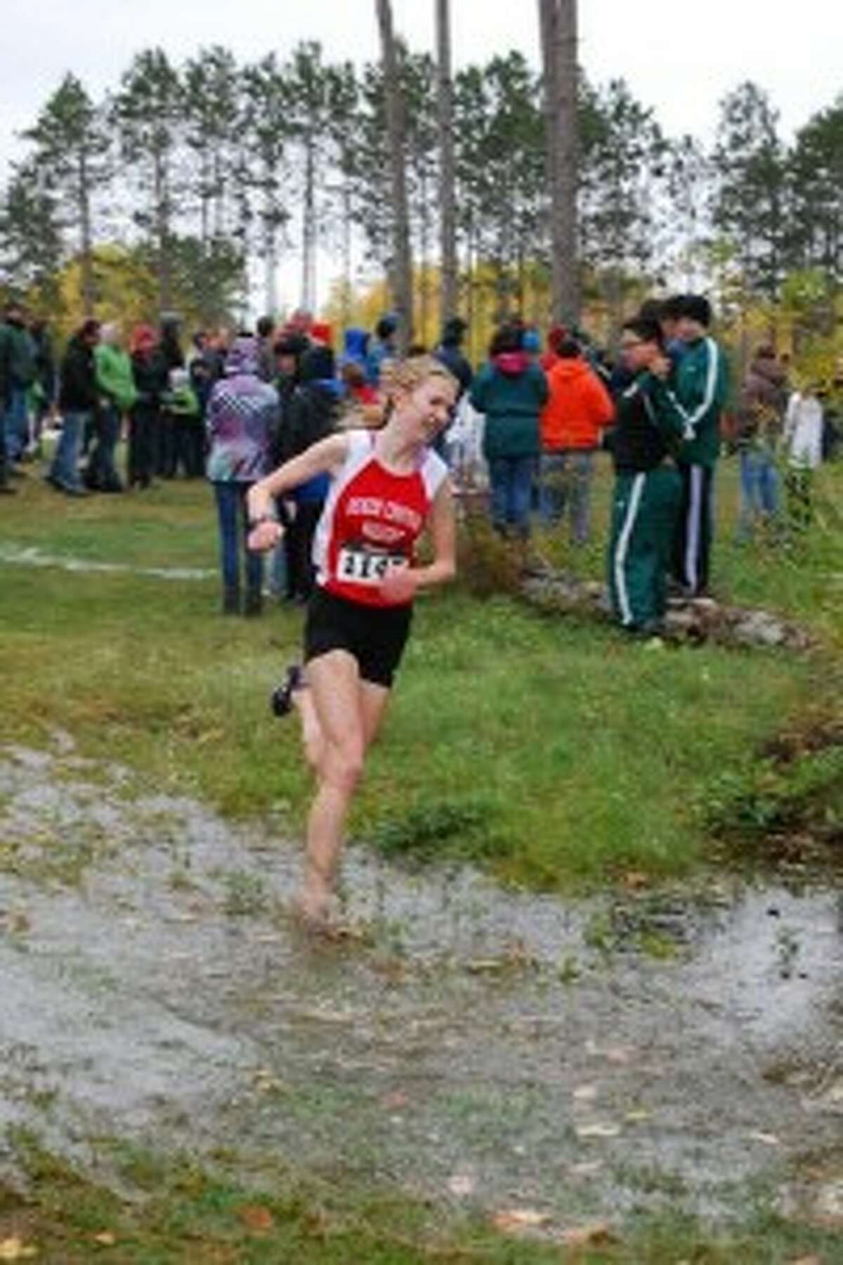 BATTLING THE ELEMENTS: Benzie junior Stephanie Schaub races through a large puddle at the two-mile mark on the course on the way to her fifth place overall finish. The Huskies had to battle through some tough weather during the Manistee National meet. (Courtesy Photo)