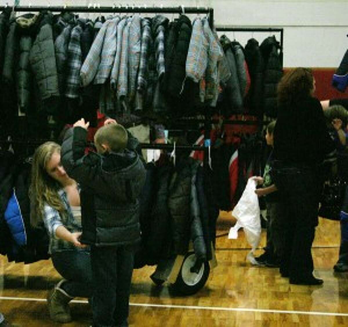 SUITING UP: A volunteer helps a student try on a new coat at the drive. (Photo/Bryan Warrick)