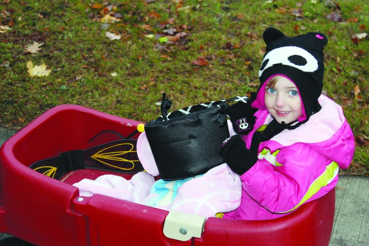 PINK BEE: Dressed for the chilly Halloween weather, pink bumble-bee Ashlyn Ott smiles as she gets a free-ride through Frankfort to collect candy. (Photos/Colin Merry)