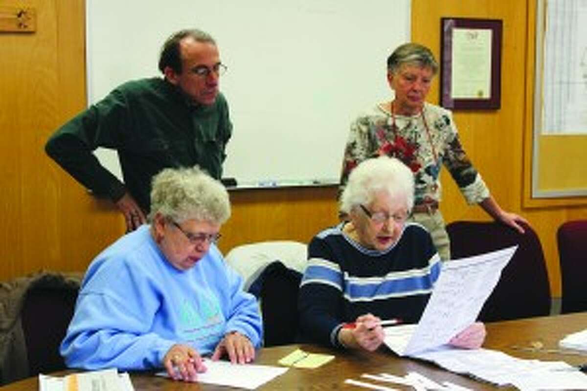 MISSING BALLOTS: Maxine Hansen and Judy Herban, election officials for Benzonia Township, read off the results of 7 absentee ballots not counted during the November 6 election while Board of Canvassers members Don Smeltzer and Margaret Wozniak watch. The ballots were left in a drawer on election night, and not found until a day later. (Photo/Colin Merry)