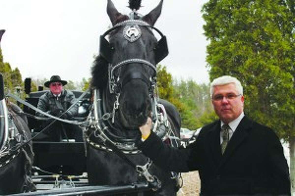 HORSE-DRAWN: Gaylord Jowett stands with Jackson, one of the horses from Black Horse Farm used to pull the hearse. (Courtesy photos)