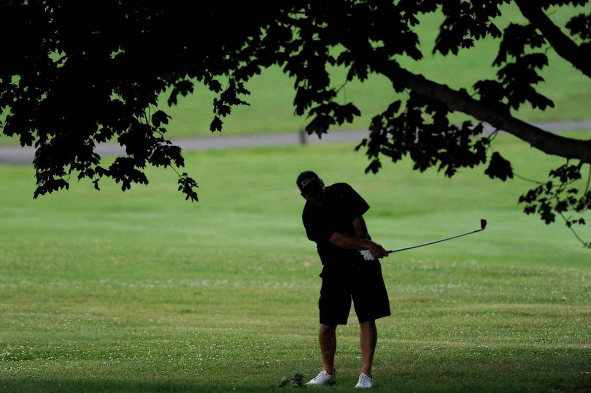 A golfer hits a shot from under a tree on the 2nd hole during the 2018 Stamford Amateur Championship at E. Gaynor Brennan Golf Course in Stamford, Conn. on Sunday, June 24, 2018. The city Golf Commission is one of many that has trouble filling seats.