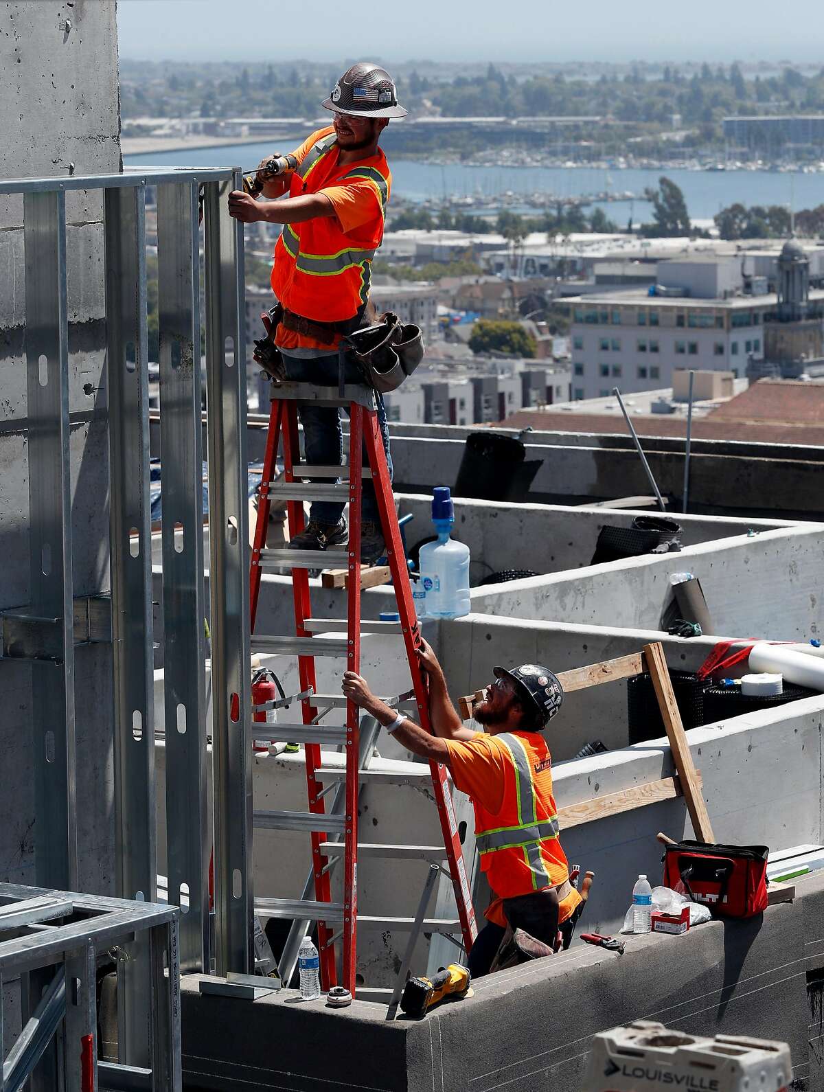 Workers construct a facade wall from metal studs at the construction site of a 20-story residential building going up on the 1700 block fo Webster Street in Oakland Calif., on Wednesday, July 17, 2019. Oakland�s downtown has long been revered as hip, electric and historic. Five years ago, the area underwent a transformation minority-owned nail salons shuttered and were instead replaced by hipster bike shops. Now, stores and other businesses are facing a similar transformation as cranes dot the skyline and 20-story buildings go up. One downtown block, near 17th and Webster, is a microcosm of the change that�s coming once again to downtown Oakland. There are three big development projects currently under construction on that block - two of which will have 20-story towers.