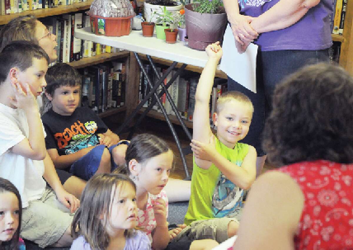 KNOWS THE ANSWER: A young boy raises his hand to answer a question during Chase Township Public Library’s summer reading program on Wednesday. The theme of the program is “Dig into Reading,” and children learned about unique plants on Wednesday. (Star photo/Kyle Leppek)