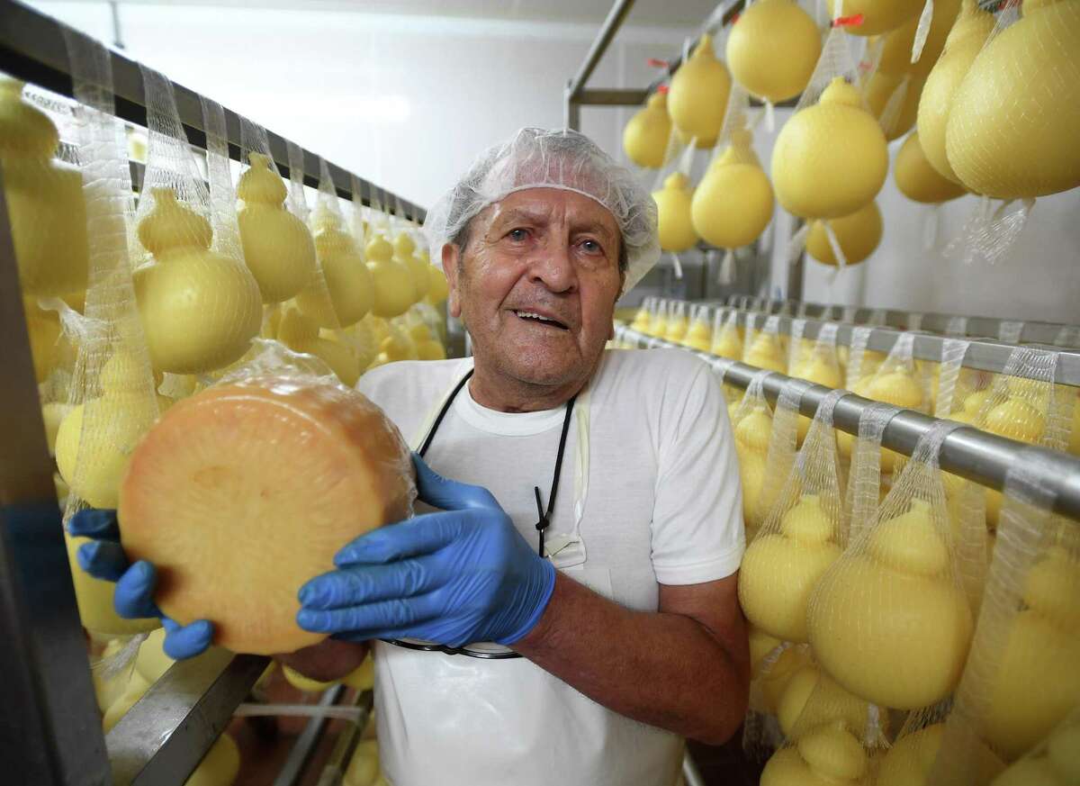 Company founder Lino Liuzzi holds an aged wheel of Sabbioso, a hard parmesan-style cheese used for grating, at Liuzzi Cheese in Hamden.