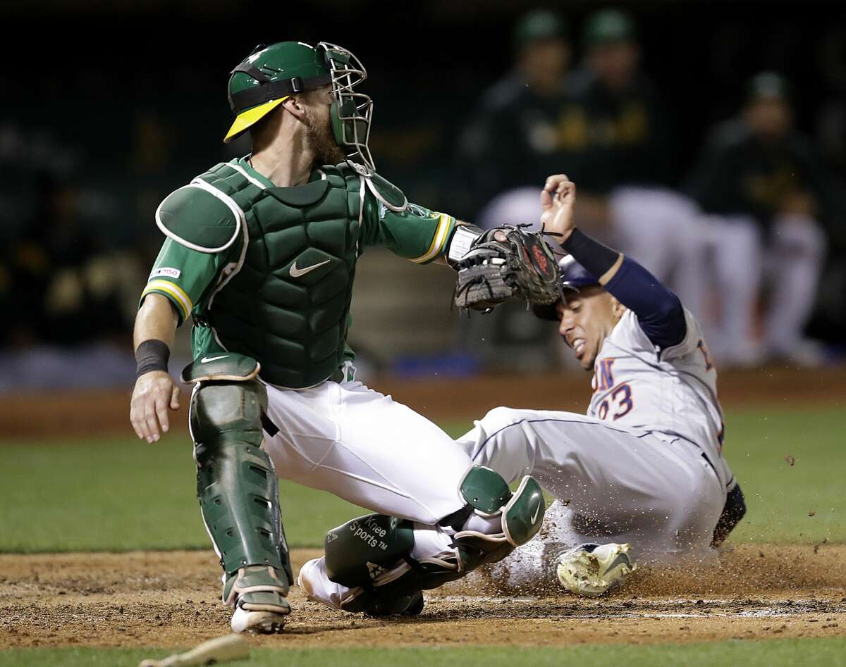 Houston Astros' Michael Brantley, right, scores past Oakland Athletics catcher Chris Herrmann during the sixth inning of a baseball game Friday, Aug. 16, 2019, in Oakland, Calif. (AP Photo/Ben Margot)