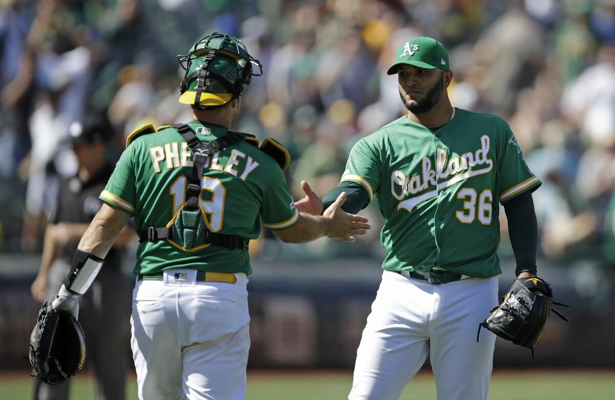 Oakland Athletics pitcher Yusmeiro Petit, right, celebrates the team's 8-4 win over the Houston Astros with catcher Josh Phegley at the end of a baseball game Saturday, Aug. 17, 2019, in Oakland, Calif. (AP Photo/Ben Margot)