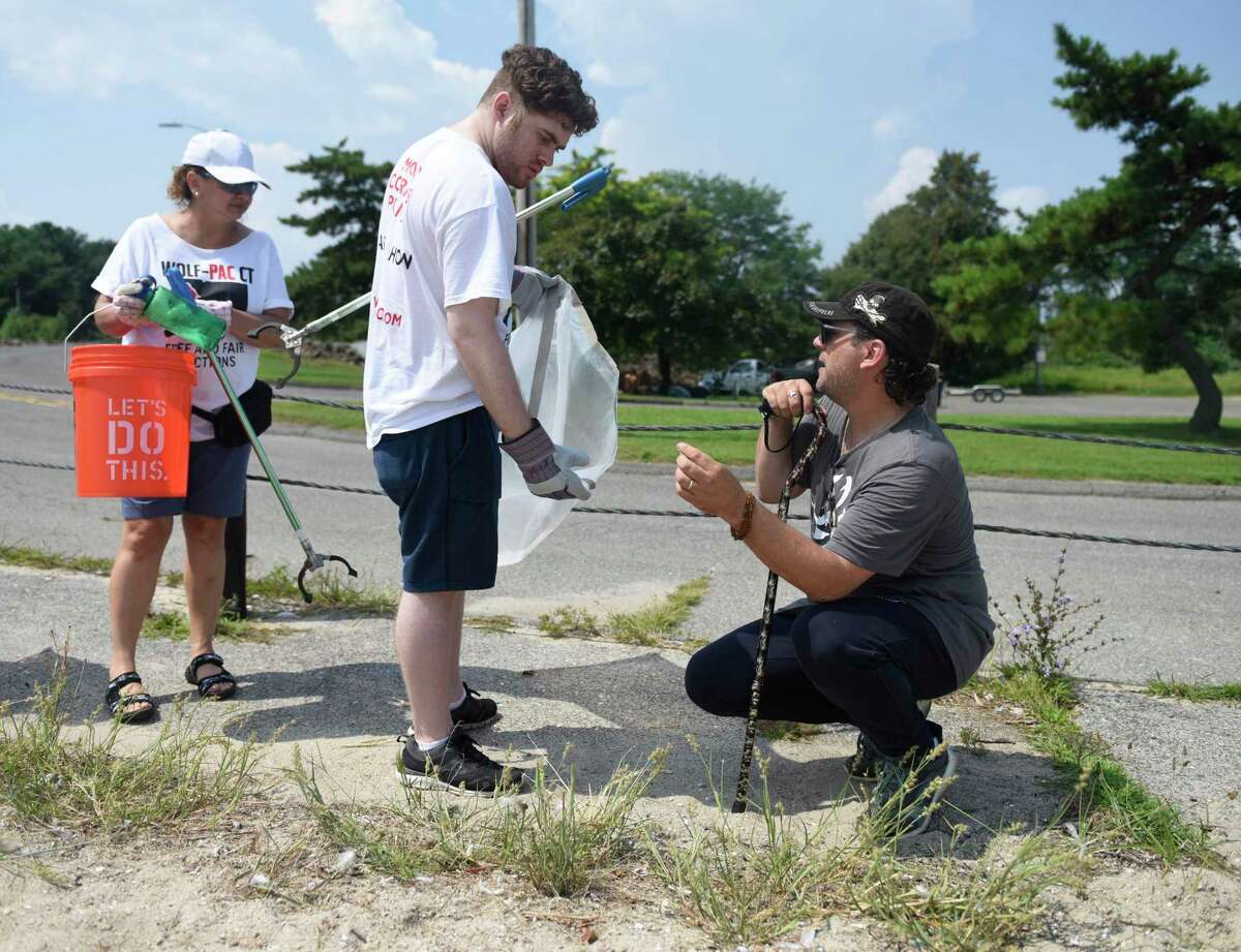 At left, State Rep. David Michel, D-Stamford, right, with volunteers from Wolf-PAC CT Sonia Zelaya and Mike Antonakos, participate in the cleanup effort. Michel teamed up with Wolf-PAC, a group seeking to make the government more accountable for the people and end corruption, to clean the beach. Above, volunteers from Wolf-PAC CT Sholom Dawit, left, David Briggs, center, and Christian Sylvia clean up trash and debris from West Beach in Stamford on Sunday.