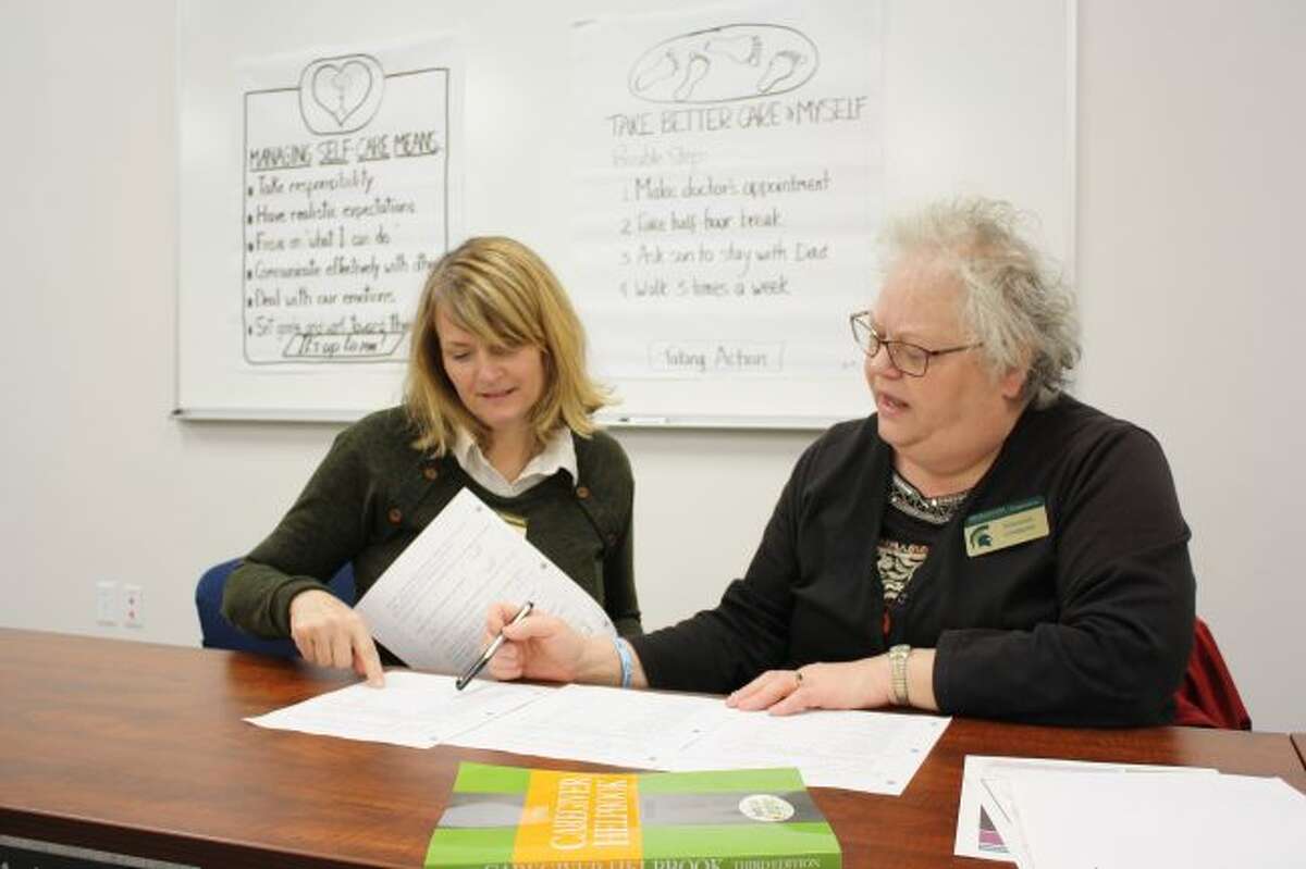 Pamela Daniels (left) and Shannon Lindquist, both educators with Michigan State University Extension, review the survey responses from a previous Powerful Tools for Caregivers workshop. MSUE will offer the workshop at no charge for six weeks beginning Jan. 26 in Evart. (Herald Review photo/Candy Allan)