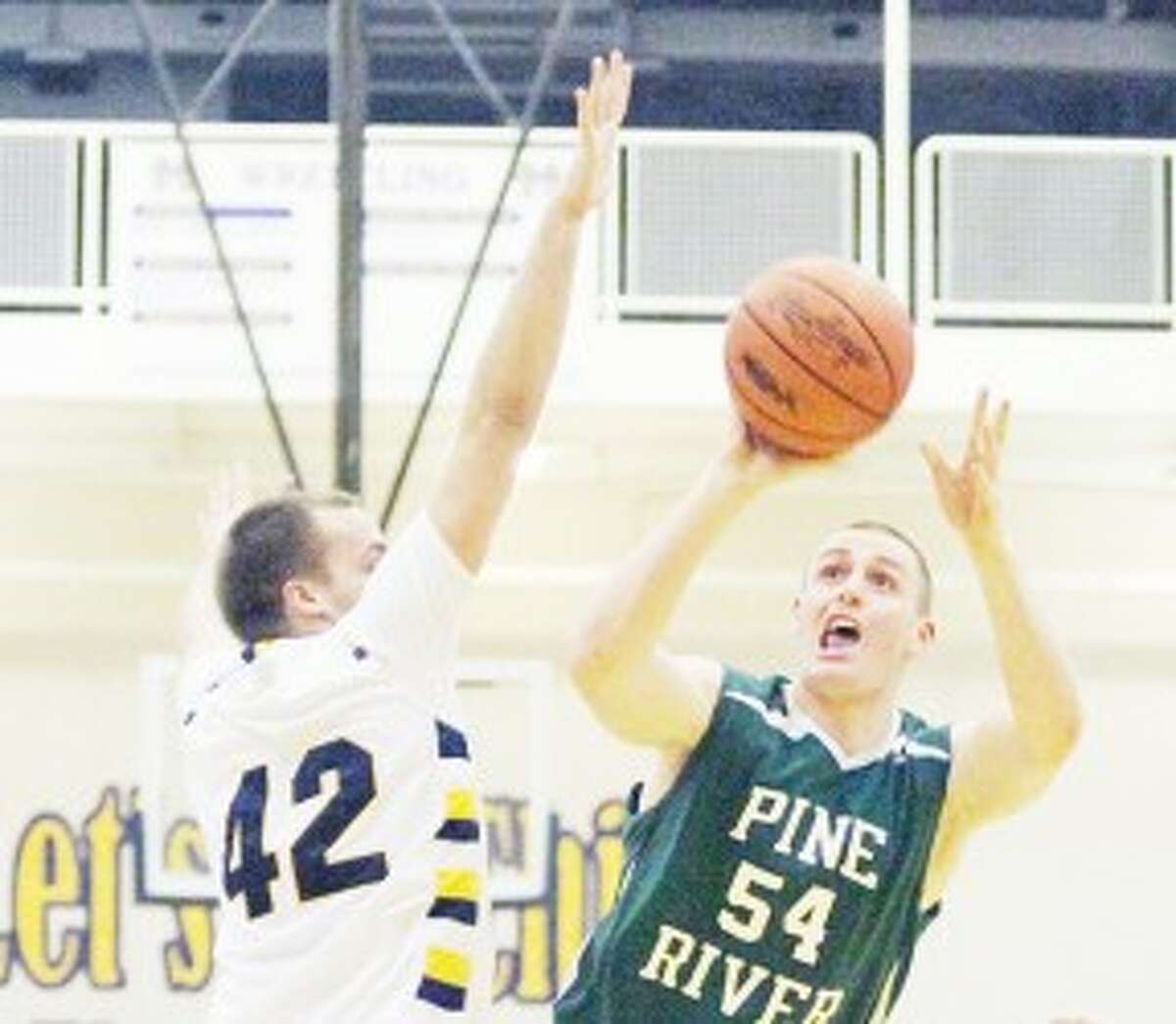 working for the win: Pine River’s Lincoln Erickson (54) tries to get a shot off over Manistee’s Jordan MacArthur during Monday’s basketball contest. (Herald Review photo/Matt Wenzel)