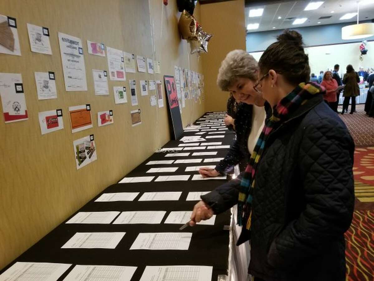(Front) Tina Swan and Linda Latin browse the silent auction items on one of the many tables set up at the Holiday Inn during the seventh annual We Care For Kids auction. Proceeds from the auction are used toward education and extra-curricular activities at Trinity Lutheran School in Reed City. (Herald Review photo/Meghan Gunther-Haas)
