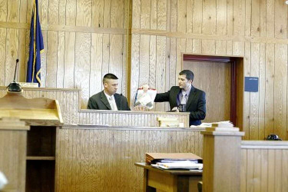 EVIDENCE: Det. Sgt. Jason Sinke, a latent fingerprint examiner from the Michigan State Police Crime Lab, passes a handgun to Osceola County Assistant Prosecutor Andy LePres. The gun has not been connected to Blake Hullihen through testimony at this time, but it is the gun that fired the bullets found at the crime scene. (Herald Review photo/Whitney Gronski-Buffa)