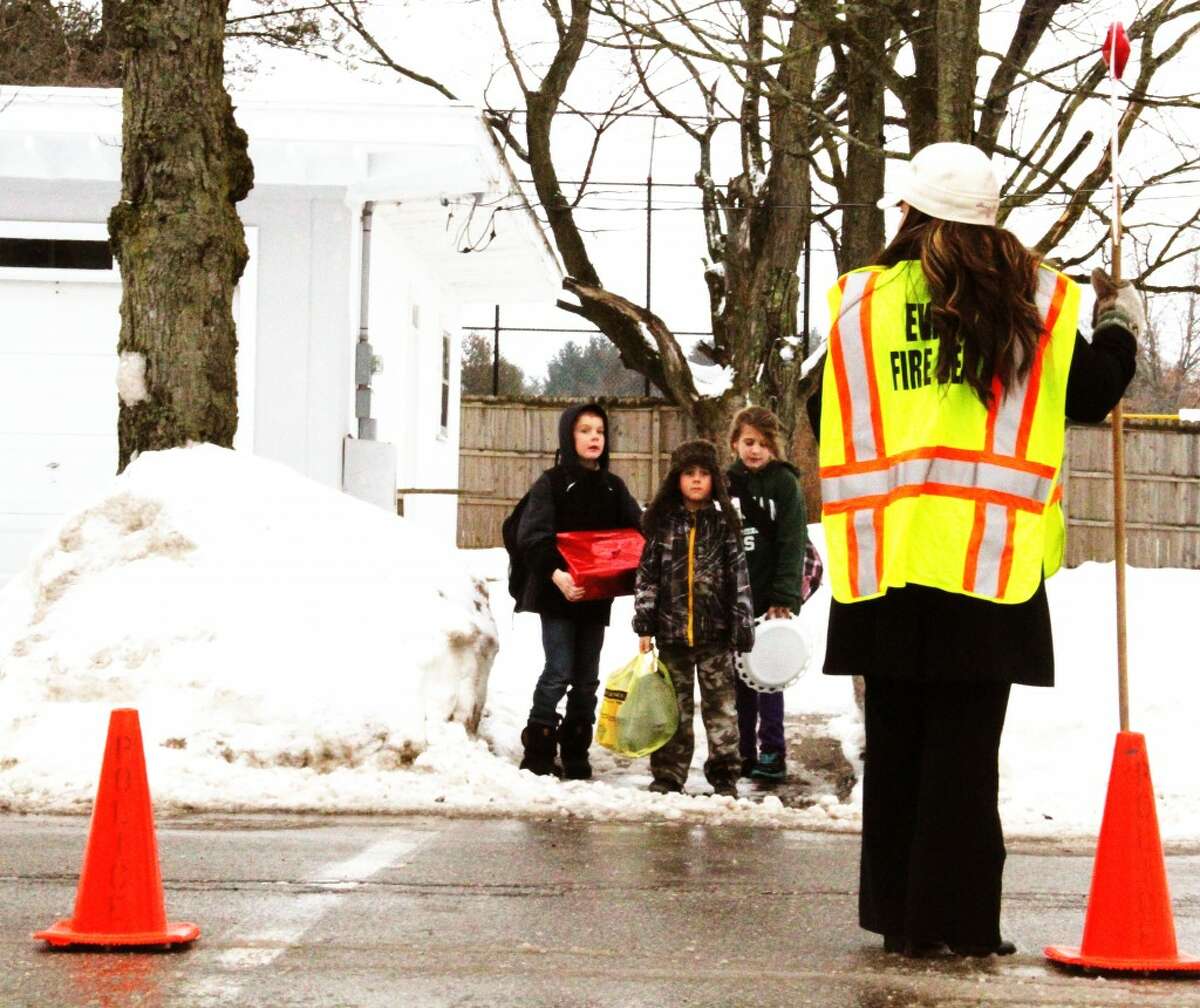 GUARD: Kelly Elder sets out cones and holds a stop sign on Cedar Street to end her shift as a crossing guard for Evart Elementary School on Thursday. The program began late last year as part of the Evart Community Watch program. (Herald Review/Sarah Neubecker photo)