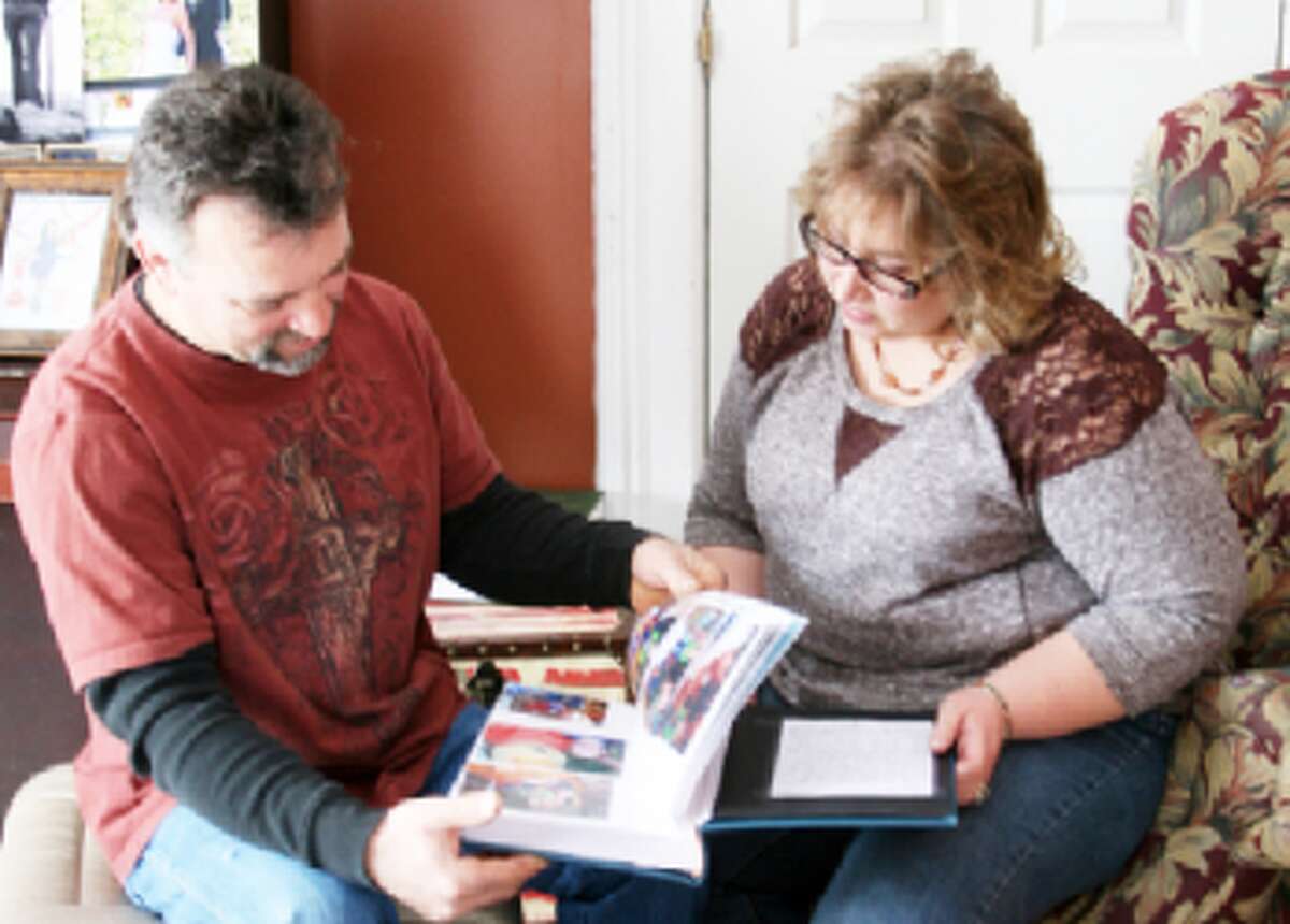 PART OF THE FAMILY: Gordon and Angie Tower look through the “life book” they made for their 4-year-old foster child they are in the process of adopting with the help of Eagle Village’s foster care program. The village is celebrating the one-year anniversary of a facility they use to instruct parents of foster care children. (Herald Review File Photo)