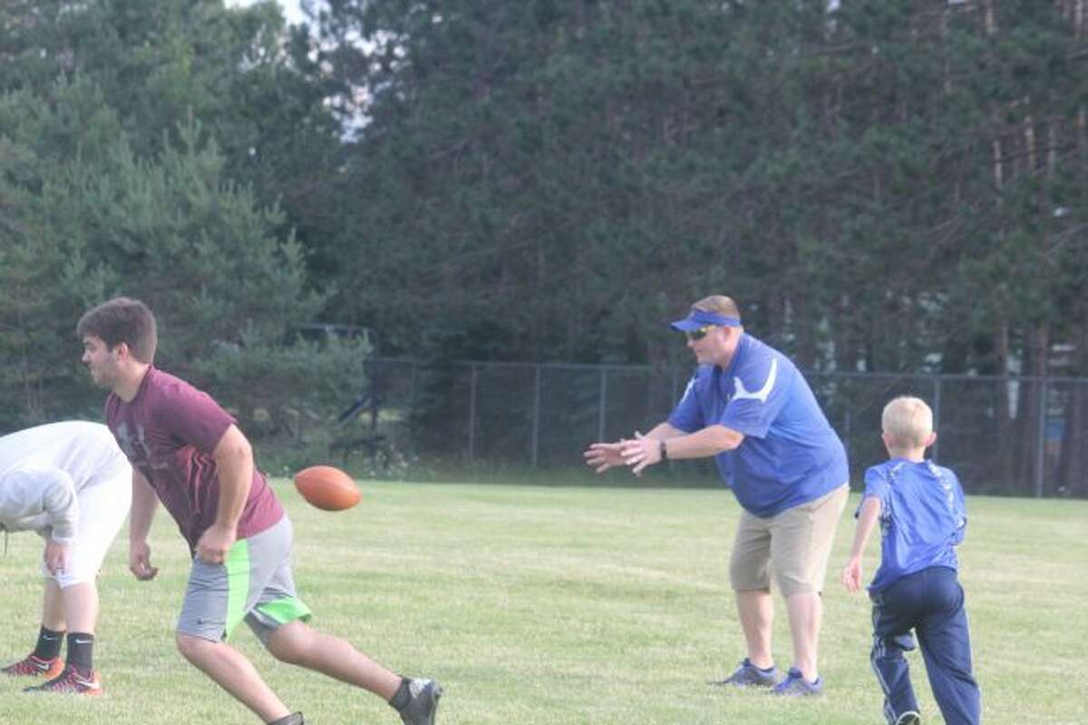 Evart football coach Pat Craven leads his team in a passing night on Sunday.