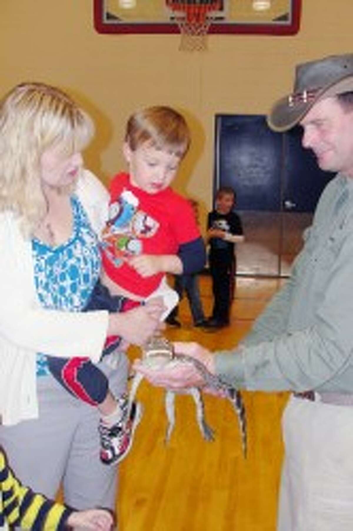 CREATURE ENCOUNTERS: Julie Hanson and her son, Ethan, get a visit from Oscar. In addition to little crocodiles, there were snakes, birds, and lizards on display. (Courtesy photo)