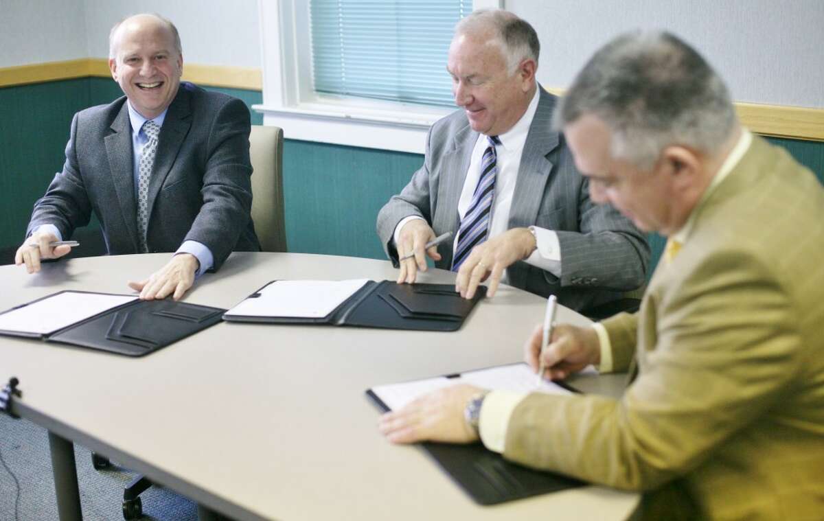 Mecosta County Commission Chair Eric O’Neil, Spectrum Health President and CEO Richard Breon and Dr. Fred Guenther, MCMC board chair, sign the merger agreement on Tuesday in MCMC’s board room. (Pioneer photos/Whitney Gronski-Buffa)