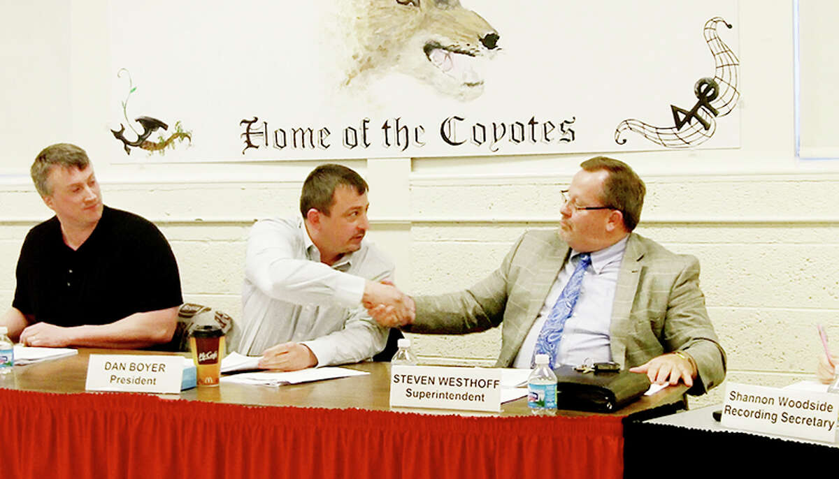 PARTING AGREEMENT: RCAPS board president Dan Boyer (center) shakes hands with superintendent Steve Westhoff after the board approved a retirement incentive for Westhoff on Monday. (Herald Review file photo)