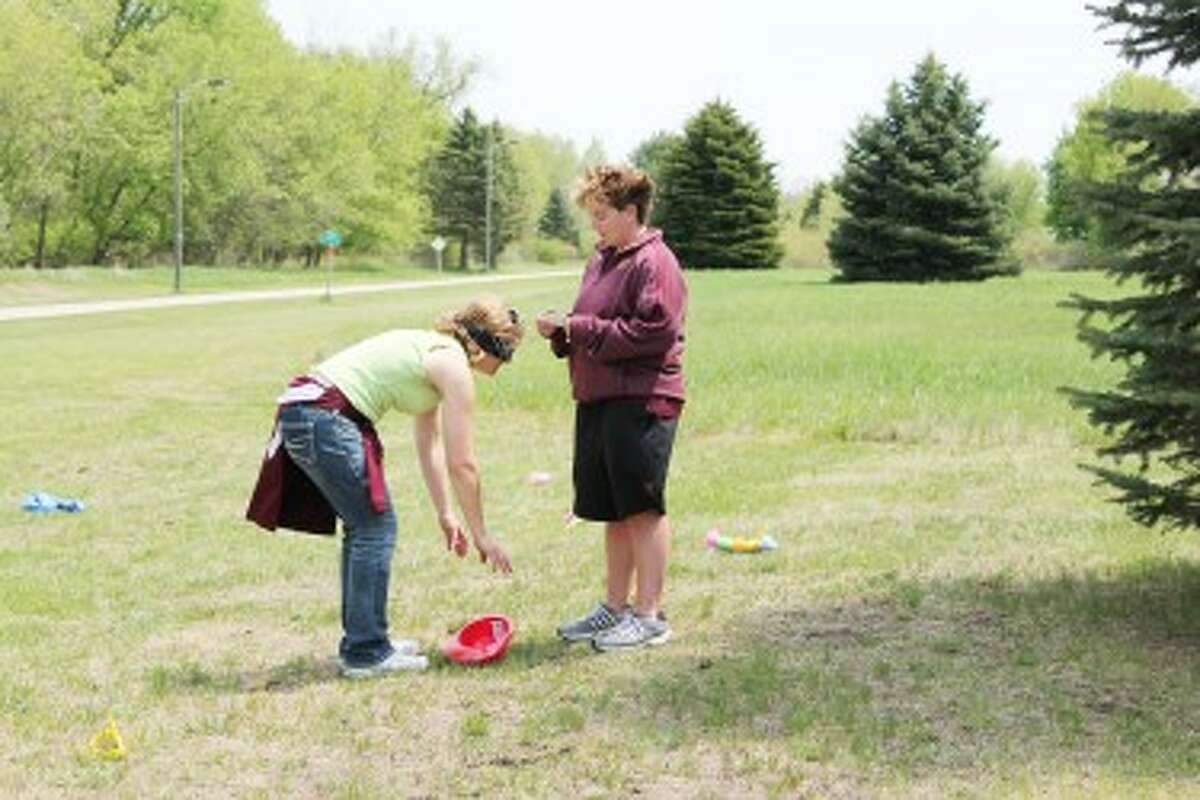 Playing for their health: Also known as the team "Treeville" Theresa Beeckman coaches Kris Spedowski in a blindfold challenge during the Heartchase event. (Herald Review/Shannon Hartley)