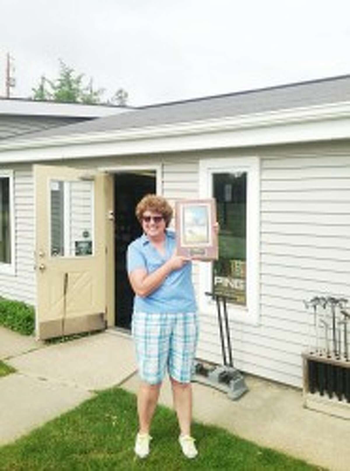 National recognition: Adrianne Danzeisen Clor poses with a plaque she received from Golf Digest after being named one of the top 100 golf fitters in the United States. Clor is originally from Tustin and owns Clor’s Outpost in Osseo with her husband, Kenneth. (Courtesy photo)